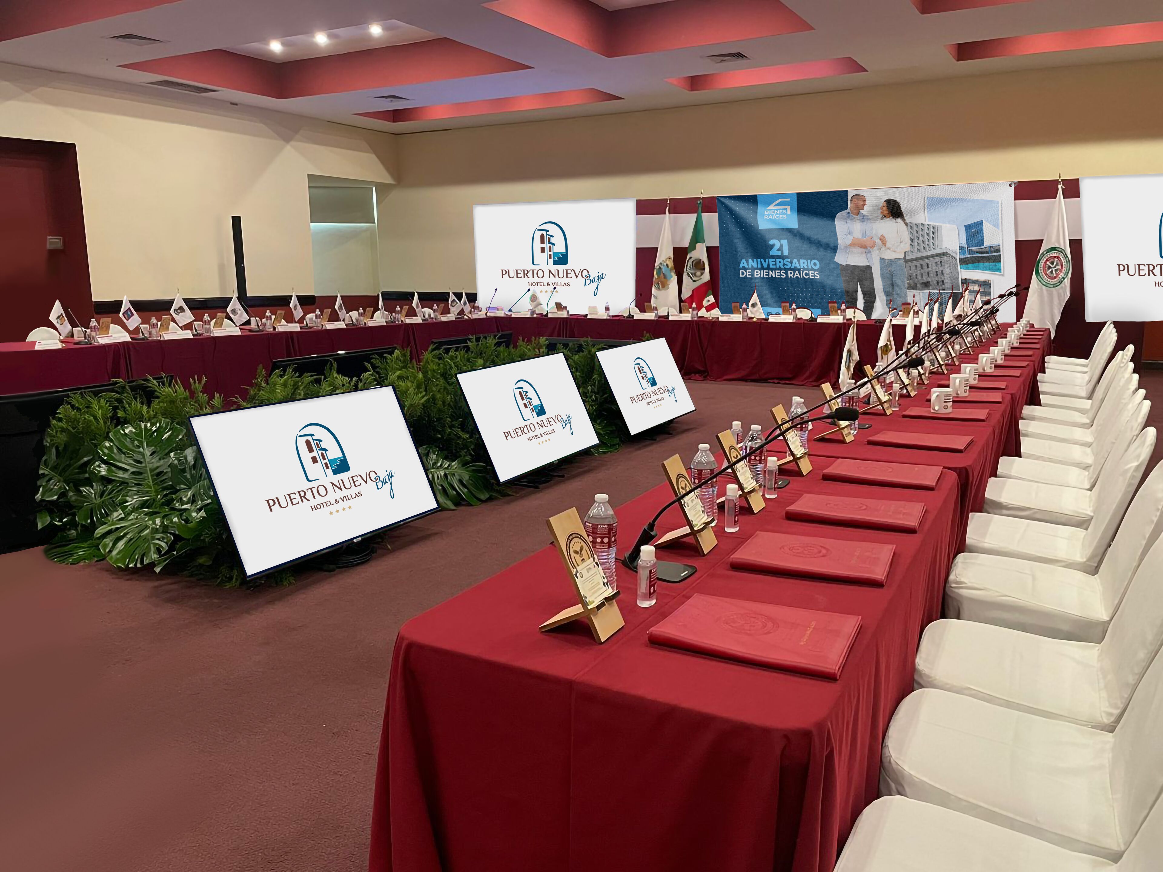 Een congreszaal met lange tafels, naamkaartjes en een spandoek voor Puerto Nuevo Hotel & Villas.