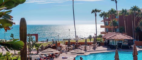 A resort with a pool, palm trees, and a view of the ocean.