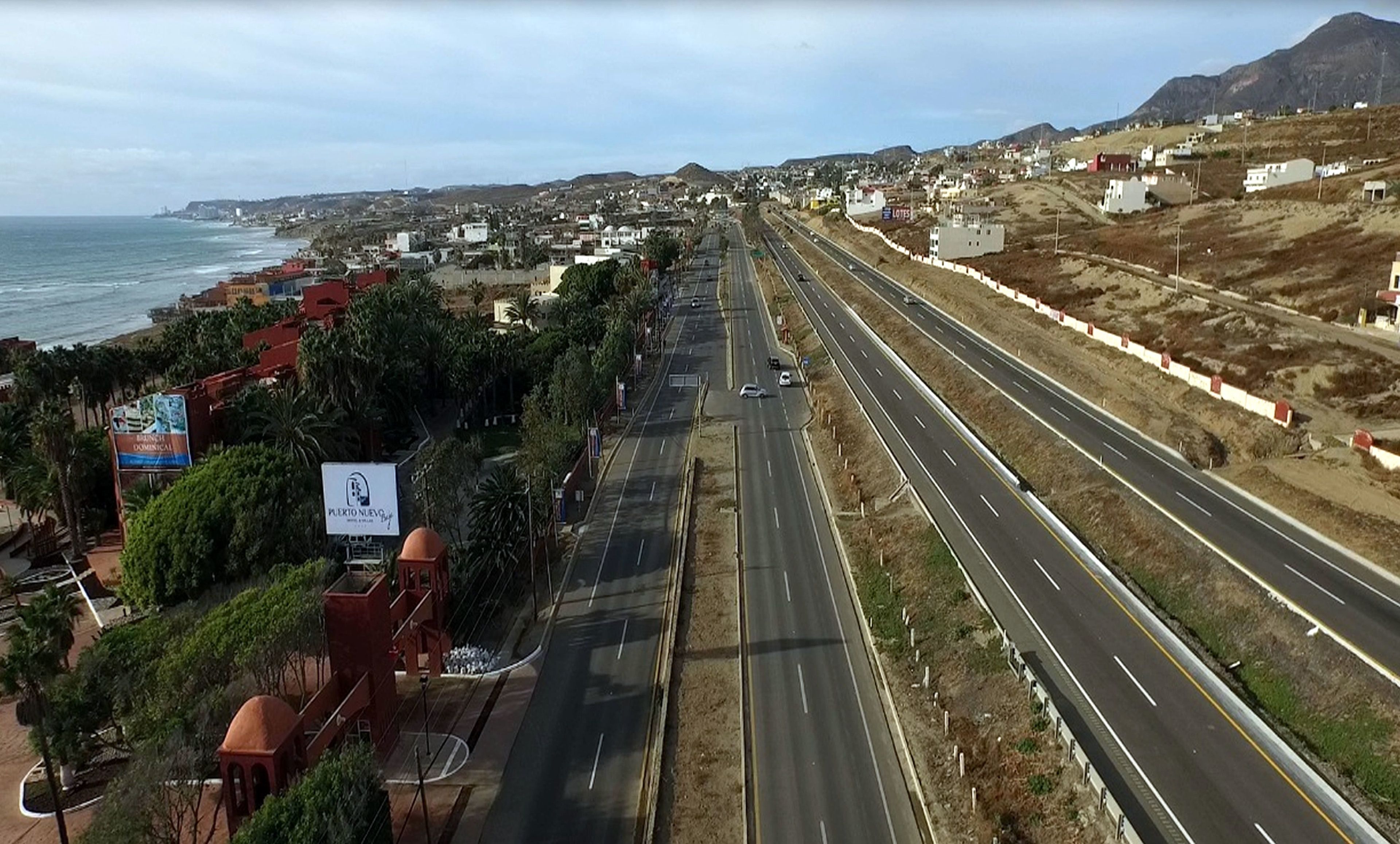 A coastal highway with multiple lanes, surrounded by residential buildings and greenery.