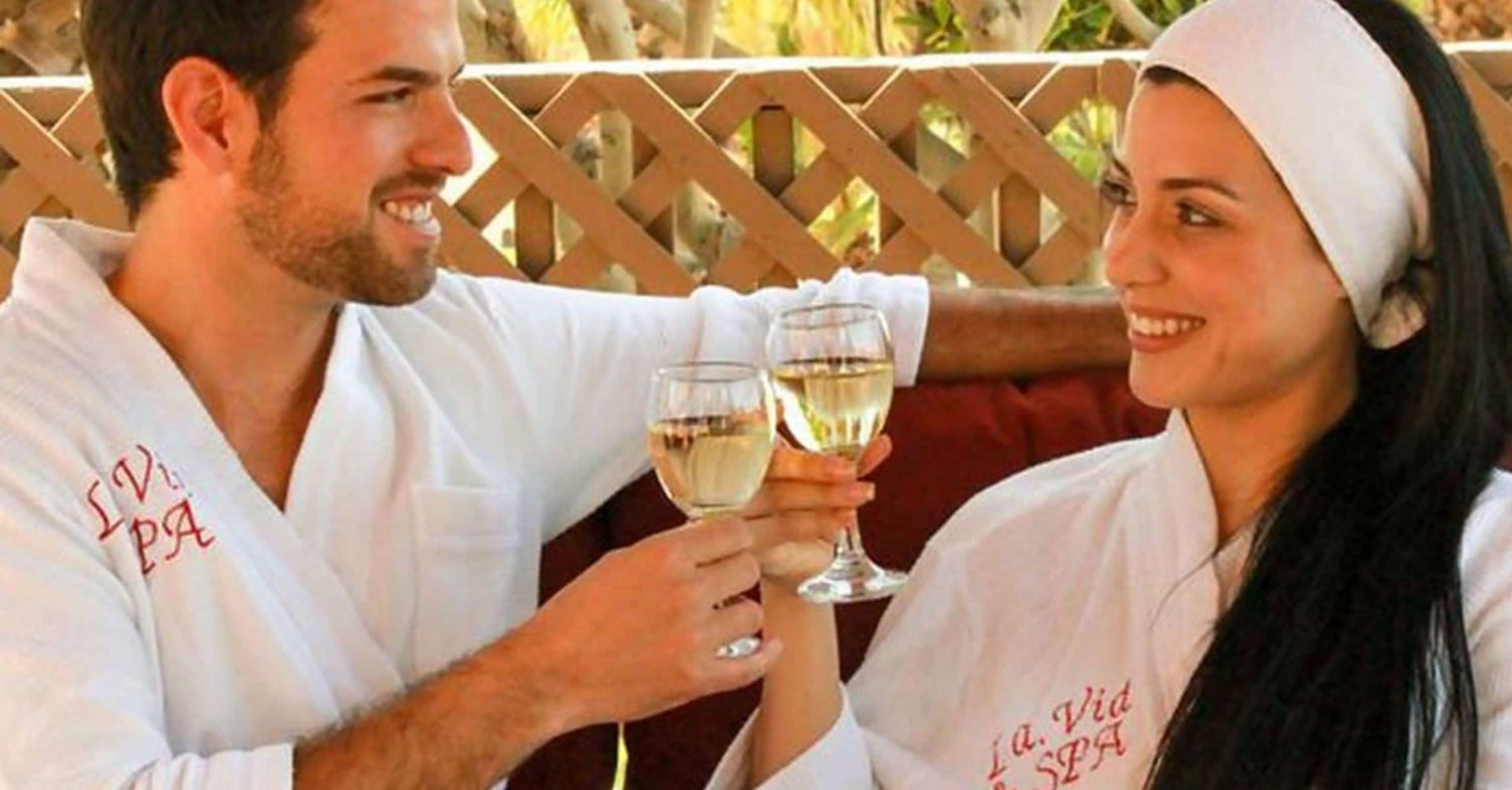 Dos personas vestidas de blanco con el texto "La Vida Spa", sosteniendo copas de vino.