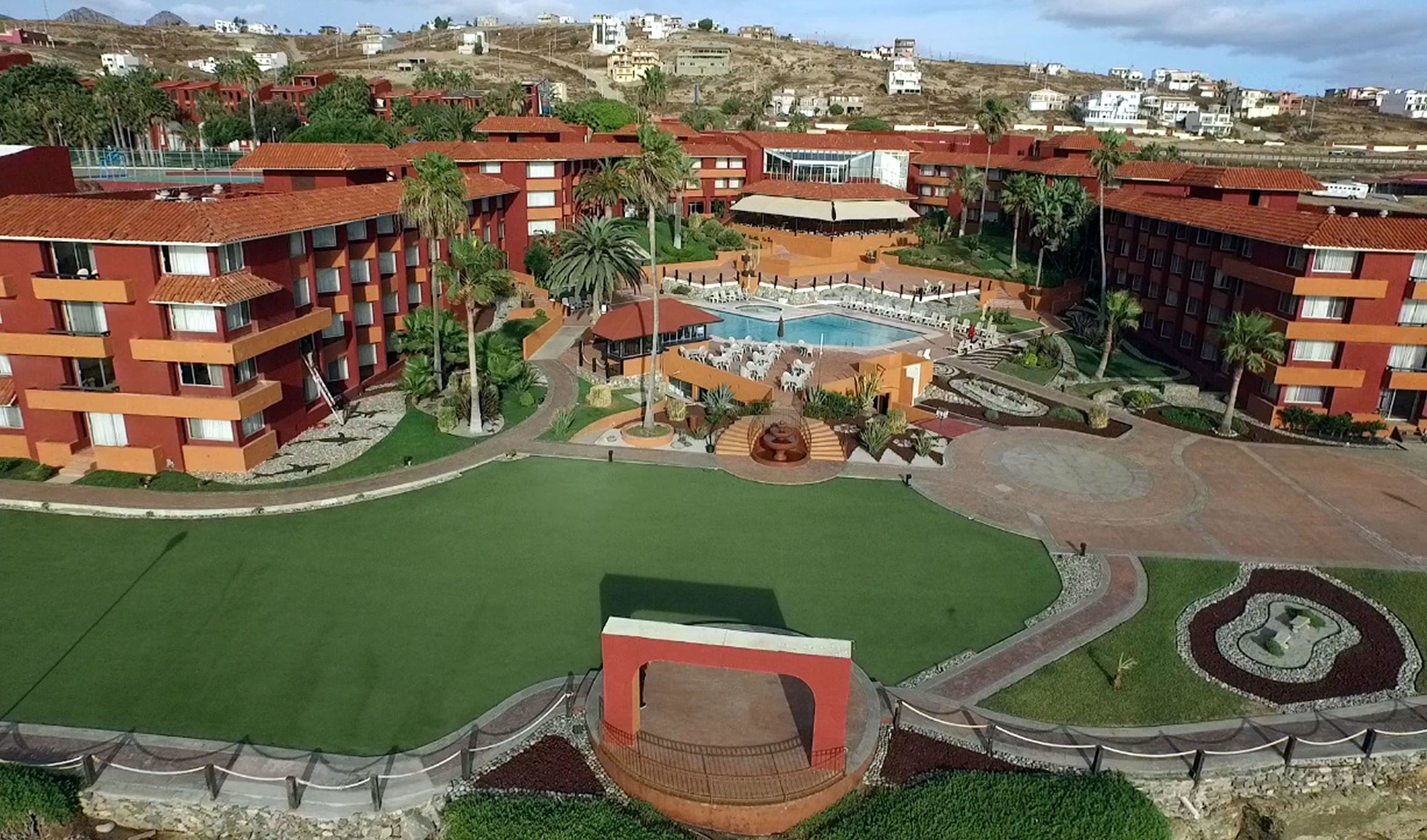 A resort with multiple red-roofed buildings, a central pool area, and landscaped gardens.