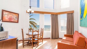 Una habitación con una mesa de comedor y sillas, un sofá, un cuadro y vistas al océano.