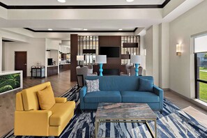 A modern living room with a blue sofa, yellow armchair, and a coffee table. - Comfort Suites Columbus East Broad (Columbus)