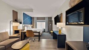 A hotel room with a bed, a desk, a chair, a sofa, a microwave, and a television. - Comfort Suites Columbus East Broad (Columbus)