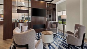 A modern hotel lobby with a large flat-screen TV, comfortable seating, and a large window offering a view of the outdoors. - Comfort Suites Columbus East Broad (Columbus)
