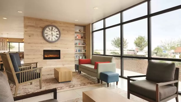 A modern living room with a fireplace, bookshelves, and large windows offering a view of the outdoors. - University Hotel - Davis Area by IHG (Dixon)