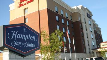 A Hampton Inn & Suites hotel building with a signboard and flag.