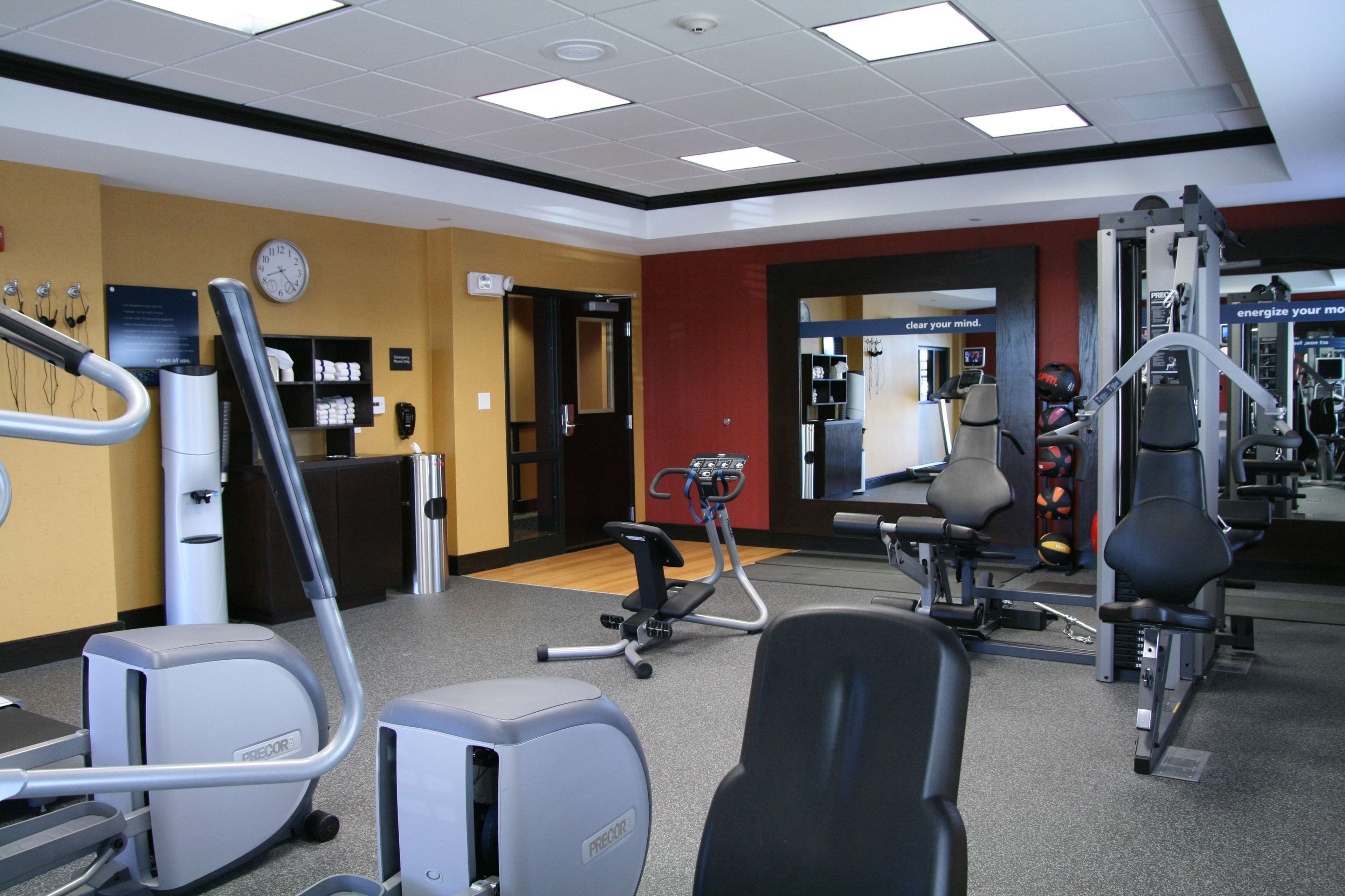 A gym with cardio machines, weight training equipment, and a mirror.