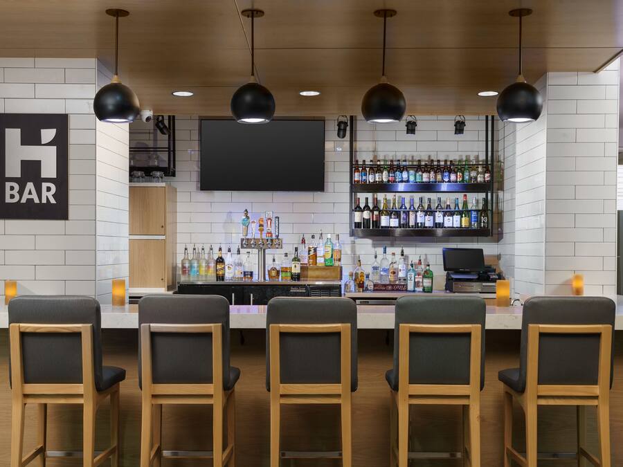 A bar area with wooden chairs, a bar counter, and a wall-mounted TV.