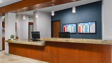 A reception desk with a granite counter, wooden paneling, and pendant lighting.