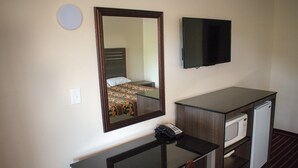 A hotel room with a bed, a desk with a chair, a microwave, and a television. - Kings Inn (Lenoir City)