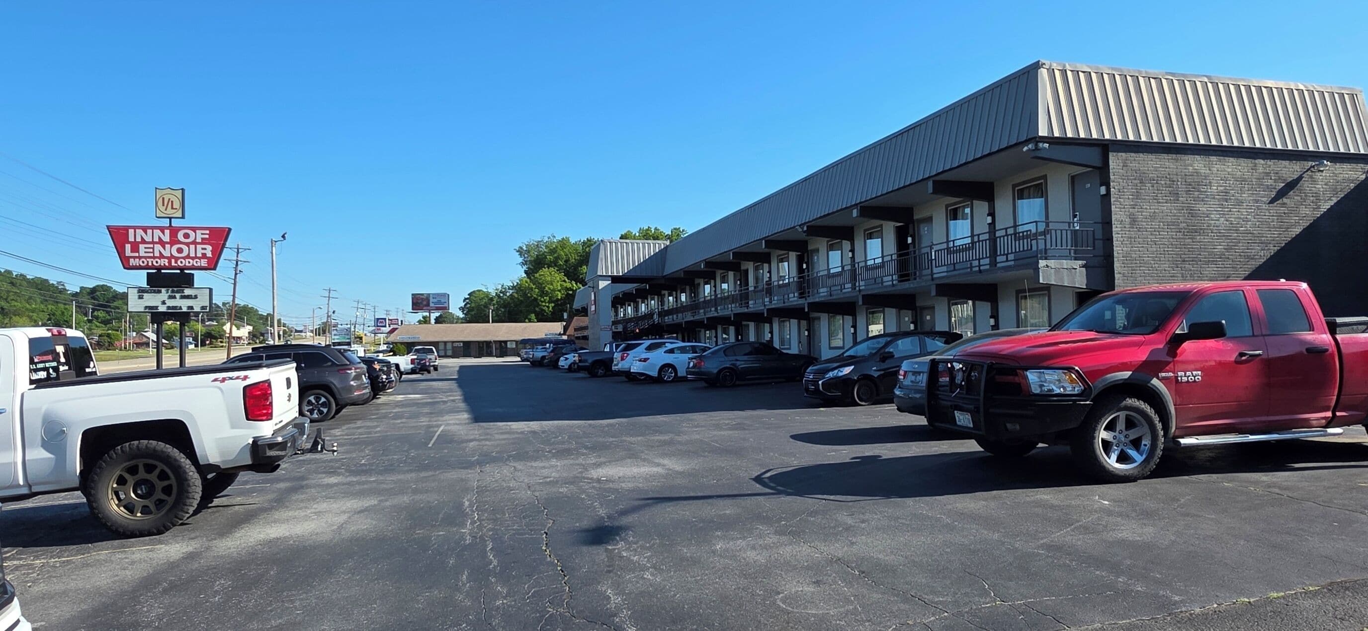 A parking lot with a motor lodge and a building with multiple balconies.