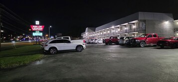Un motel con una hilera de habitaciones, un estacionamiento con varios autos y un cartel que dice Inn of Lenoir Motor Lodge.