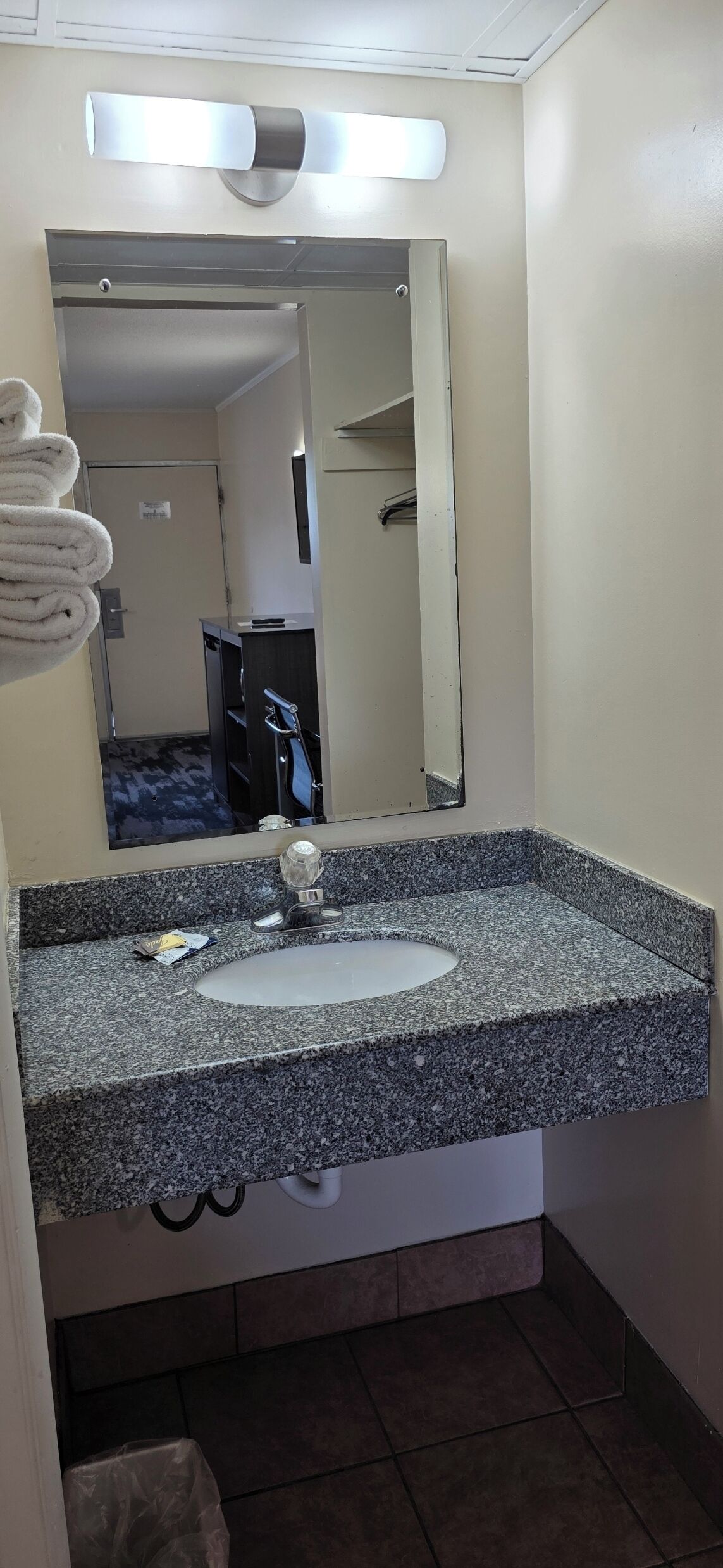 A bathroom with a granite countertop sink, a mirror, and a towel rack.