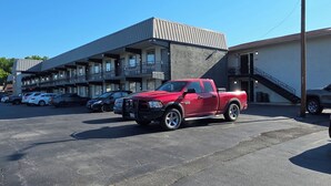 A parking lot with a red pickup truck parked in the foreground. - Inn Of Lenoir Motor Lodge (Lenoir City)
