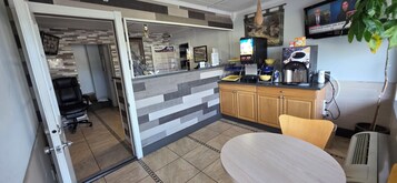 Una cocina moderna con cafetera integrada, un pequeño comedor con mesa redonda y un televisor montado en la pared.