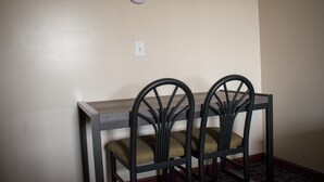 A dining area with a wooden table and two chairs with cushioned seats. - Inn Of Lenoir Motor Lodge (Lenoir City)