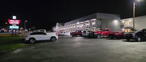 A parking lot with multiple vehicles, a building with a modern design, and a sign for the Inn of Lenoir Motor Lodge.