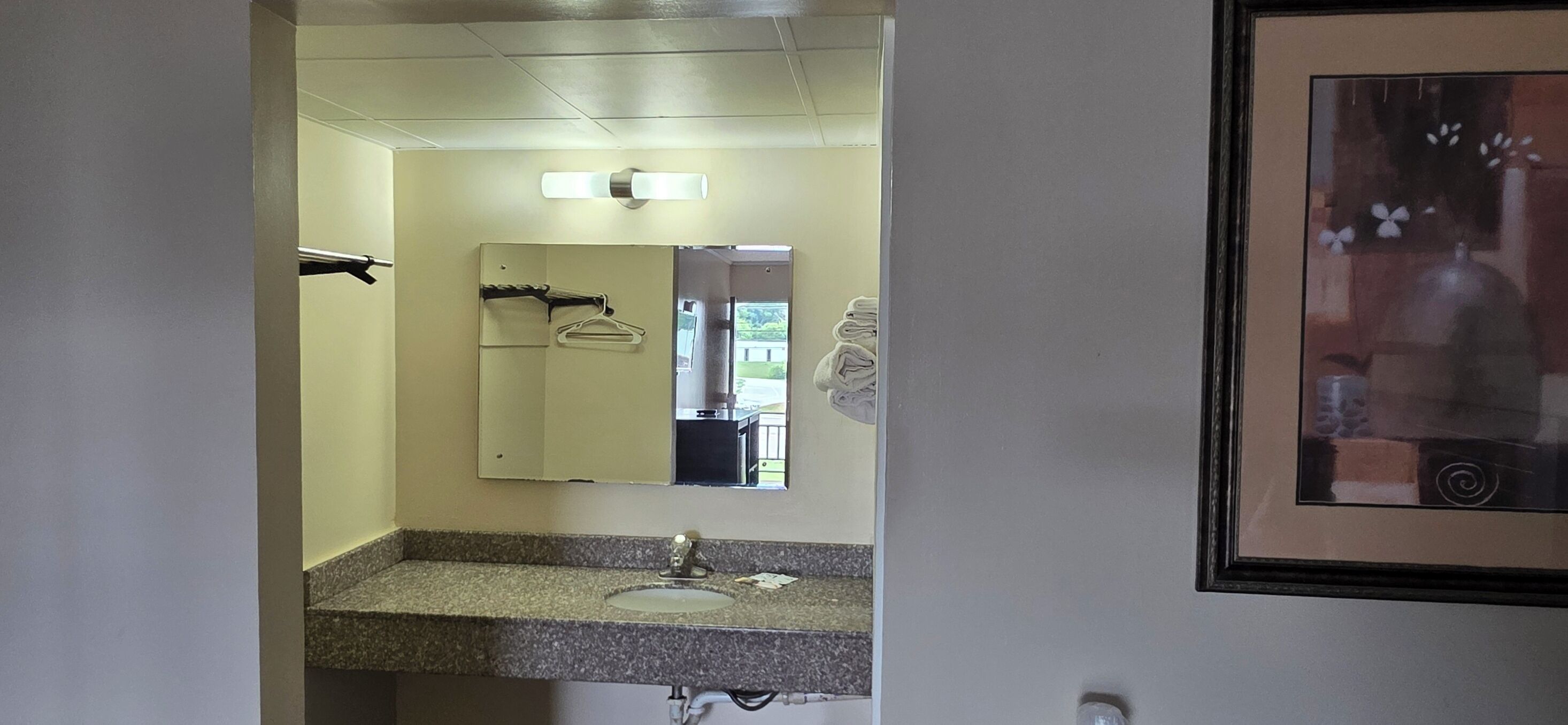 Une salle de bain avec un comptoir en granit, un lavabo, un miroir et un porte-serviettes.