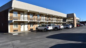 A multi-story motel with a row of rooms, a parking lot, and a small outdoor area. - Inn Of Lenoir Motor Lodge (Lenoir City)