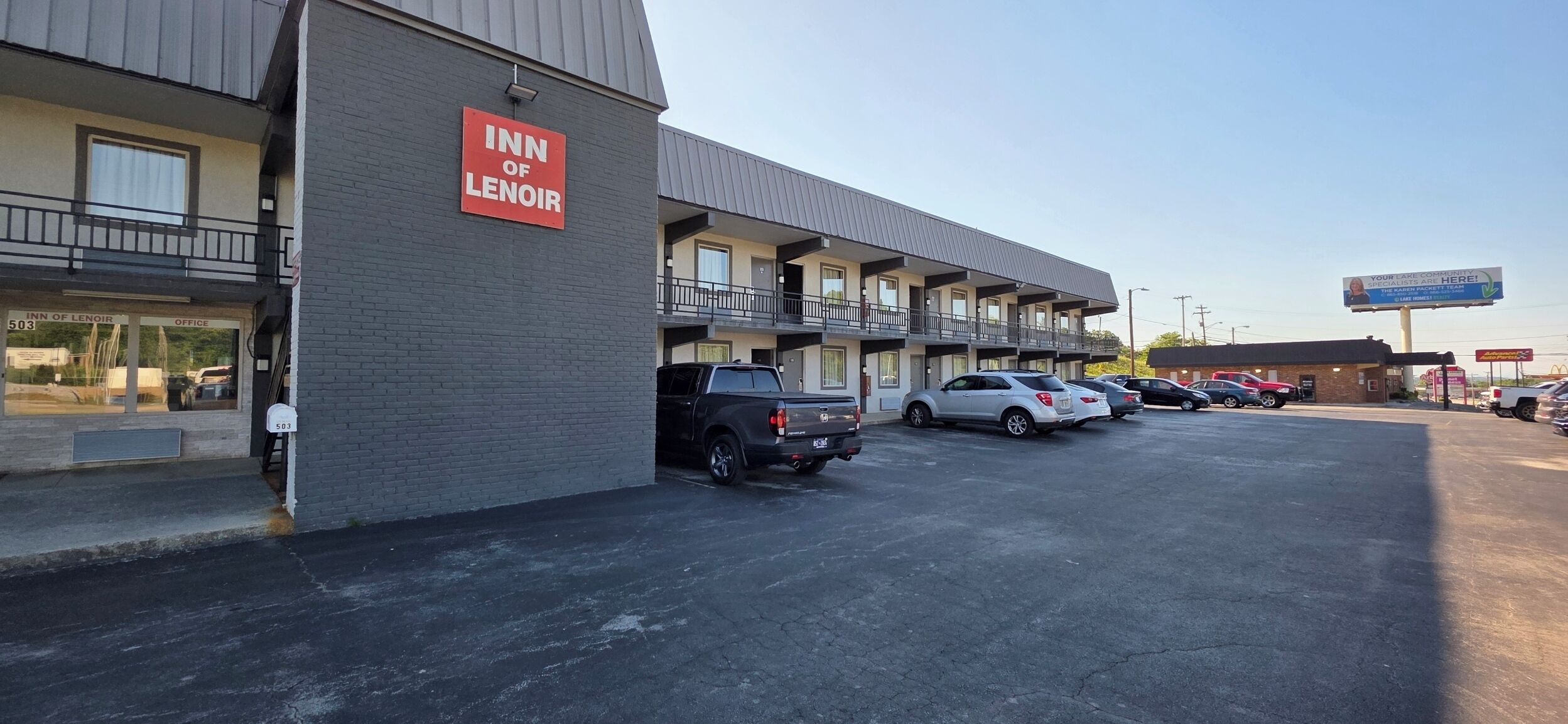 A motel with a sign reading 'Inn of Lenoir' and a parking lot with several cars.