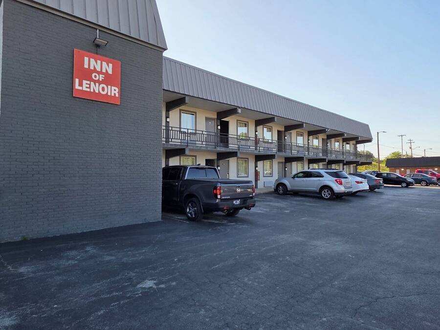 A motel with a sign reading 'Inn of Lenoir' and a parking lot with several cars.