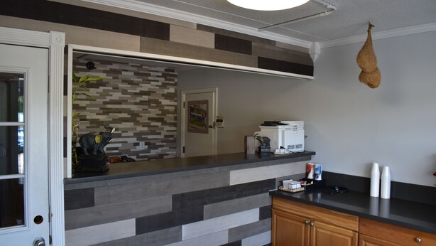 A kitchen with a modern design, featuring a striped backsplash, wooden cabinets, and a hanging light fixture. - Inn Of Lenoir Motor Lodge (Lenoir City)