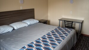 A hotel room with a large bed, a desk, and two chairs. - Inn Of Lenoir Motor Lodge (Lenoir City)