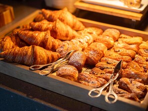 A variety of pastries on a wooden board with tongs.