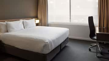 Una habitación de hotel con una cama grande, un escritorio y una silla.
