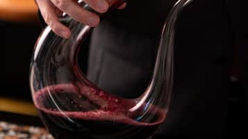 Una mano sosteniendo una copa de vino tinto.