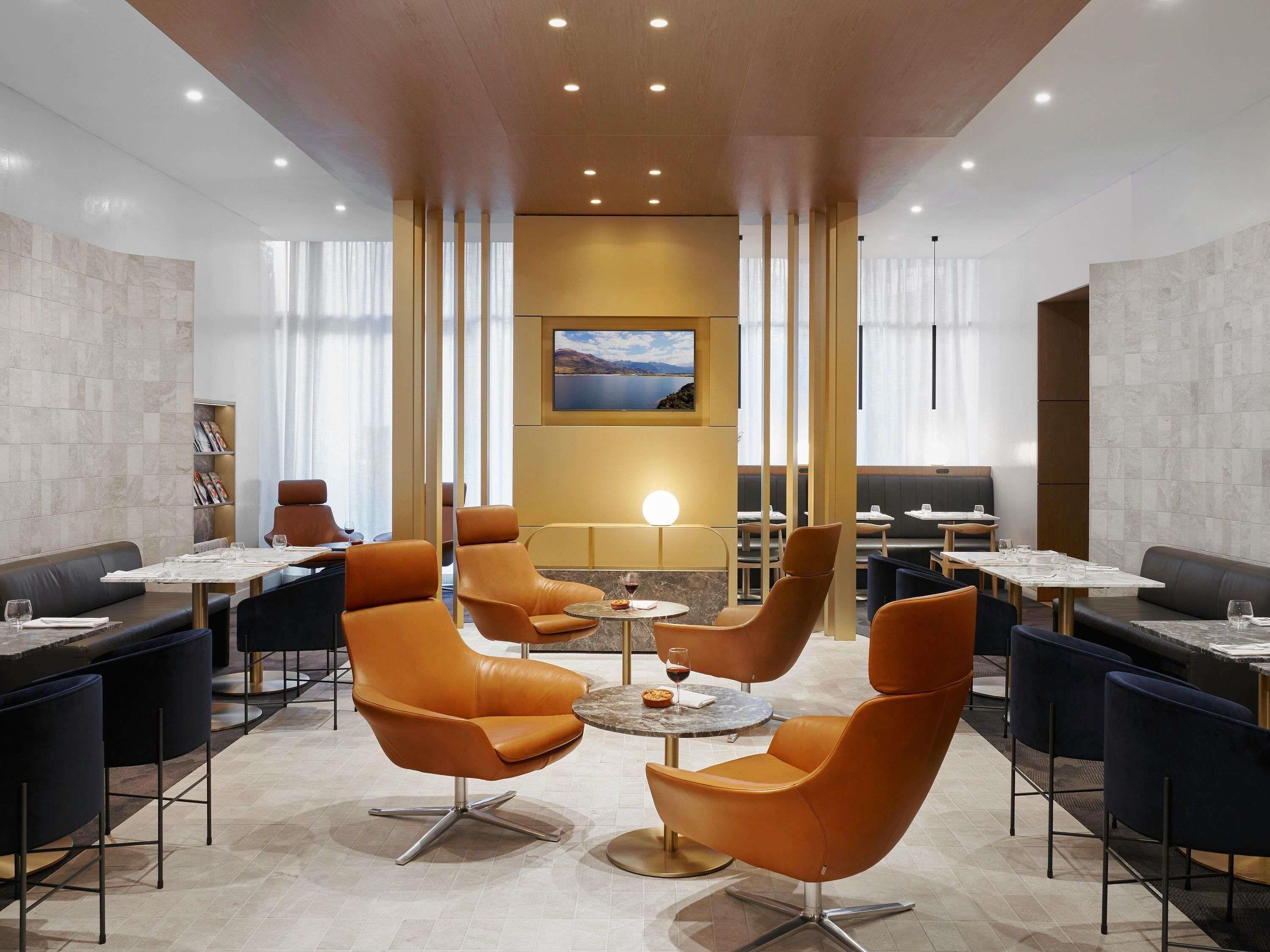 A modern dining area with leather chairs, round tables, and a large window with a view.