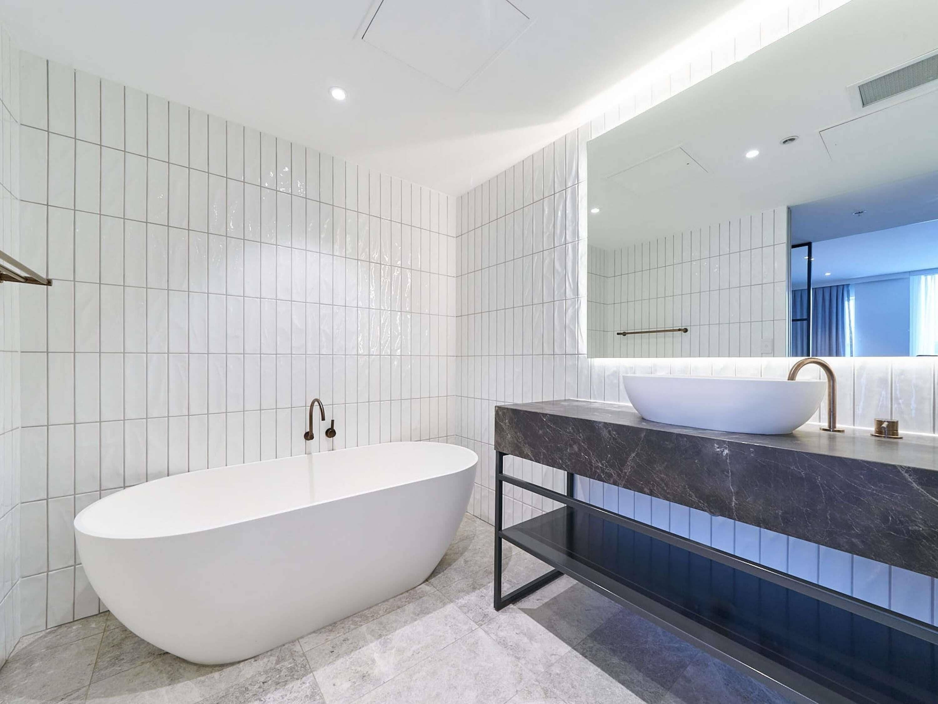A modern bathroom with a freestanding bathtub, a marble vanity, and a large mirror.