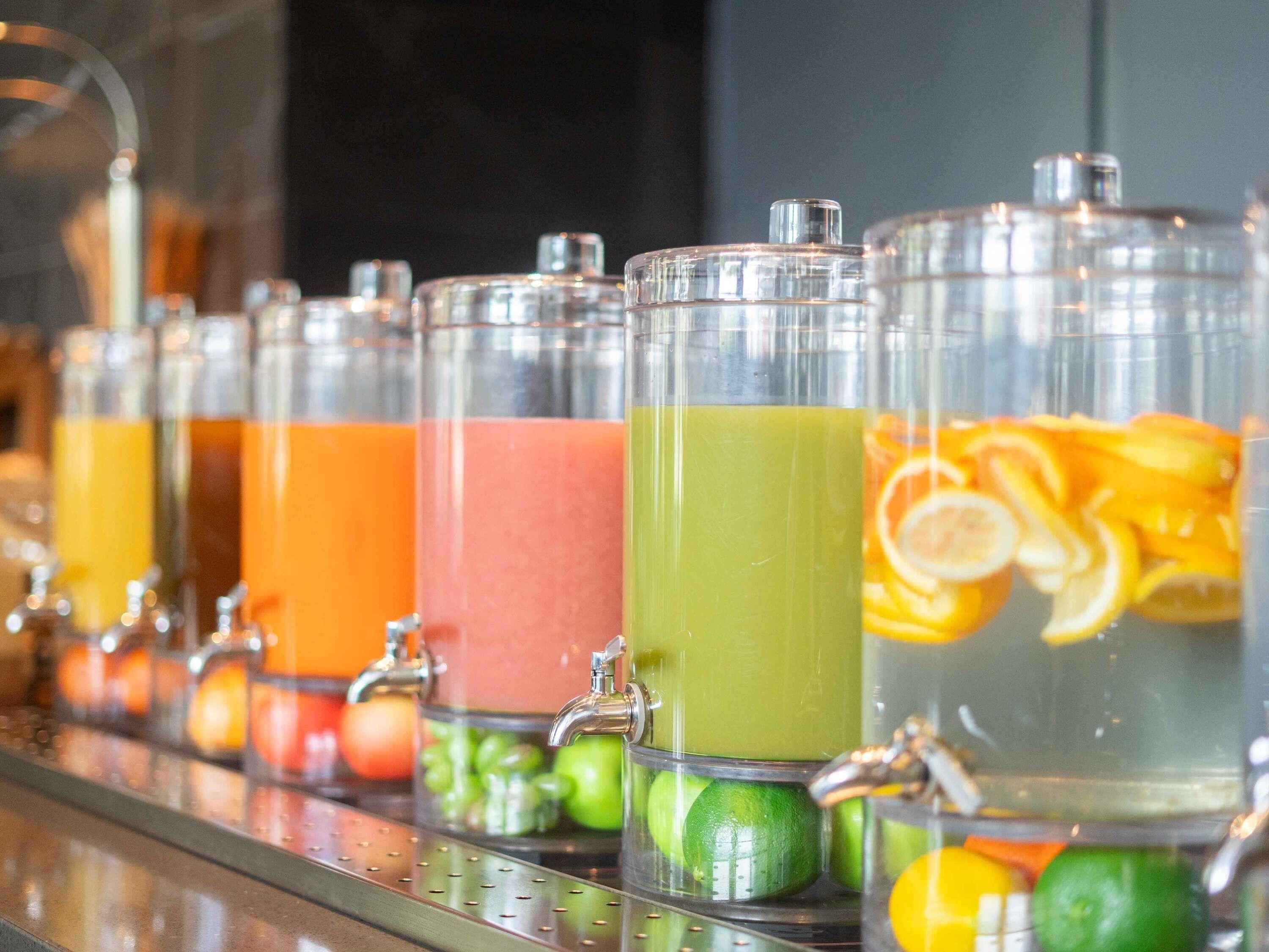 A beverage dispenser with multiple containers, each containing different colored liquids and garnished with fruits.