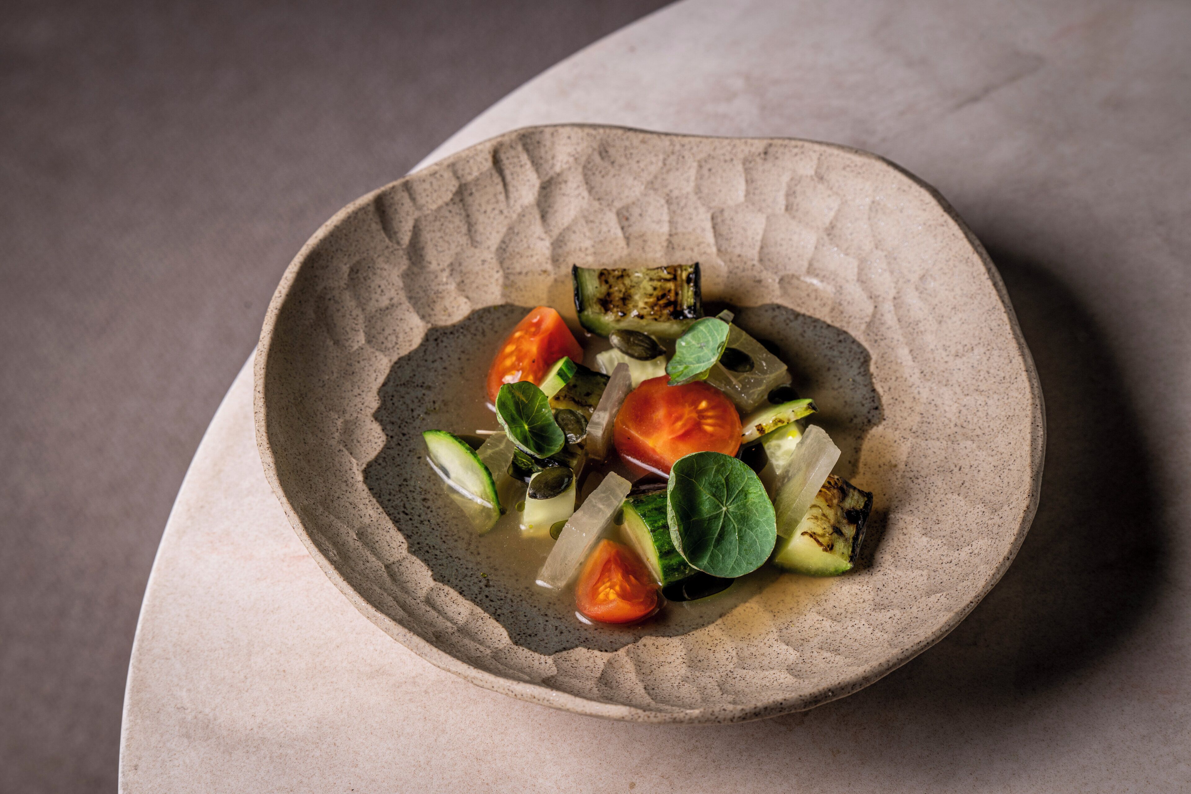 A bowl of grilled vegetables on a textured plate.