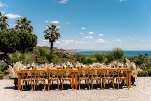 Mobiliario para comer al aire libre con vista al mar y colinas.