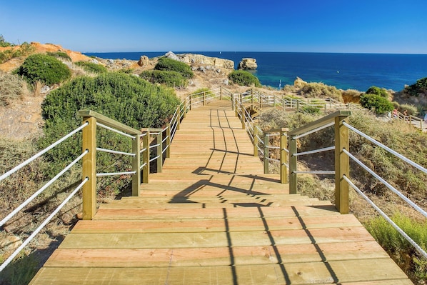 A wooden staircase leading to a coastal area with a clear view of the sea.