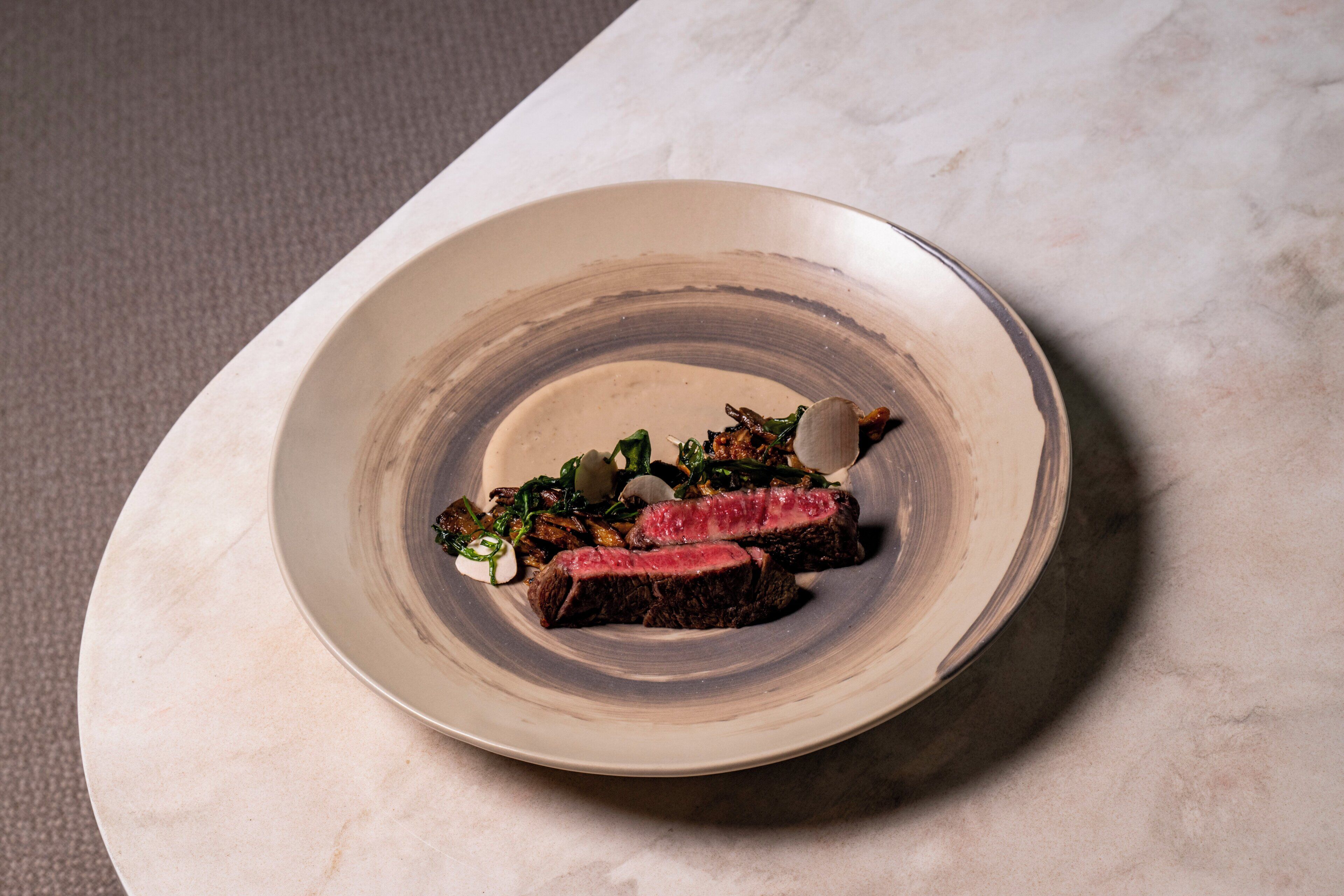 Un plato con bistec y verduras sobre una mesa de mármol.
