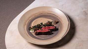 Un plato con bistec y verduras sobre una mesa de mármol.