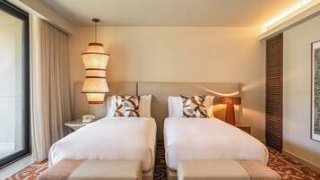 Quarto de hotel com duas camas, uma mesa de cabeceira com abajur, telefone e janela com cortinas.