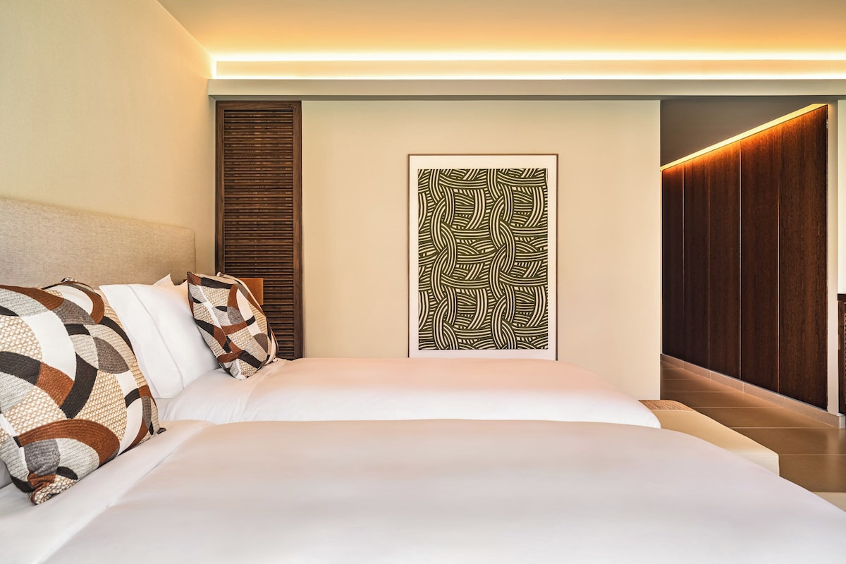 Habitación de hotel moderna con una cama grande, cabecera de madera, un panel decorativo en la pared y un armario de madera.