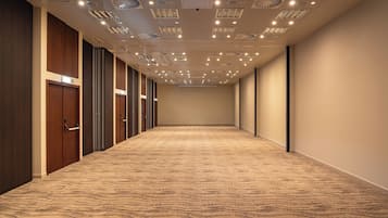 A hotel corridor with carpeted floors, wooden doors, and recessed lighting on the ceiling.