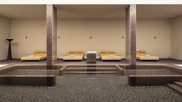 Un área de spa con un jacuzzi central, cuatro sillones beige y suelo de baldosas.