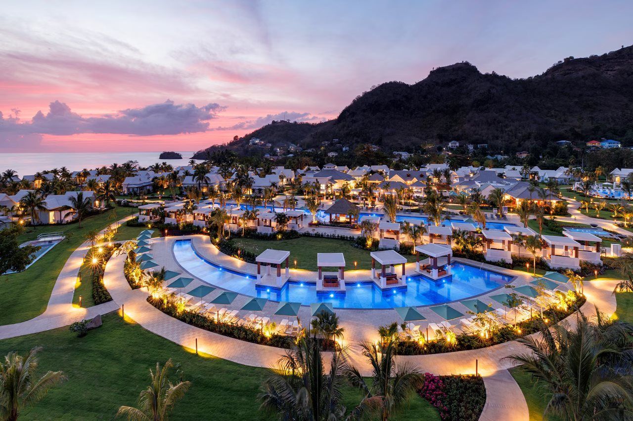 A resort with multiple swimming pools, guest villas, and a mountainous backdrop.