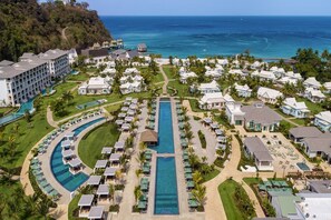 A resort with multiple swimming pools, guest villas, and a view of the ocean.