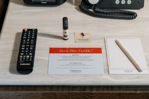 A remote control, a bottle of lotion, a pillow mist card, a card with a message, and a pencil on a table.