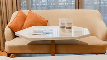 A beige sofa with two orange pillows, a white table with a magazine, and two bottles labeled "Parkroyal on Beach Road, Singapore".