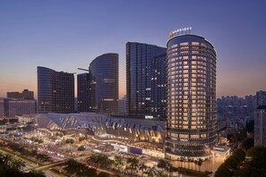 A modern hotel with a curved facade, multiple high-rise buildings, and a well-lit plaza with palm trees. - Nanning Marriott Hotel (Nanning)