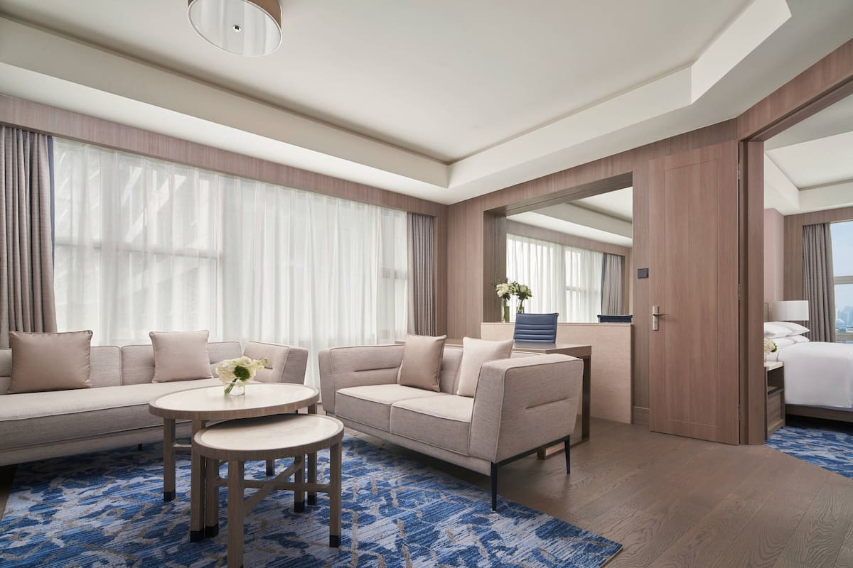 Una habitación de hotel moderna con un sofá, dos mesas redondas y una cama.