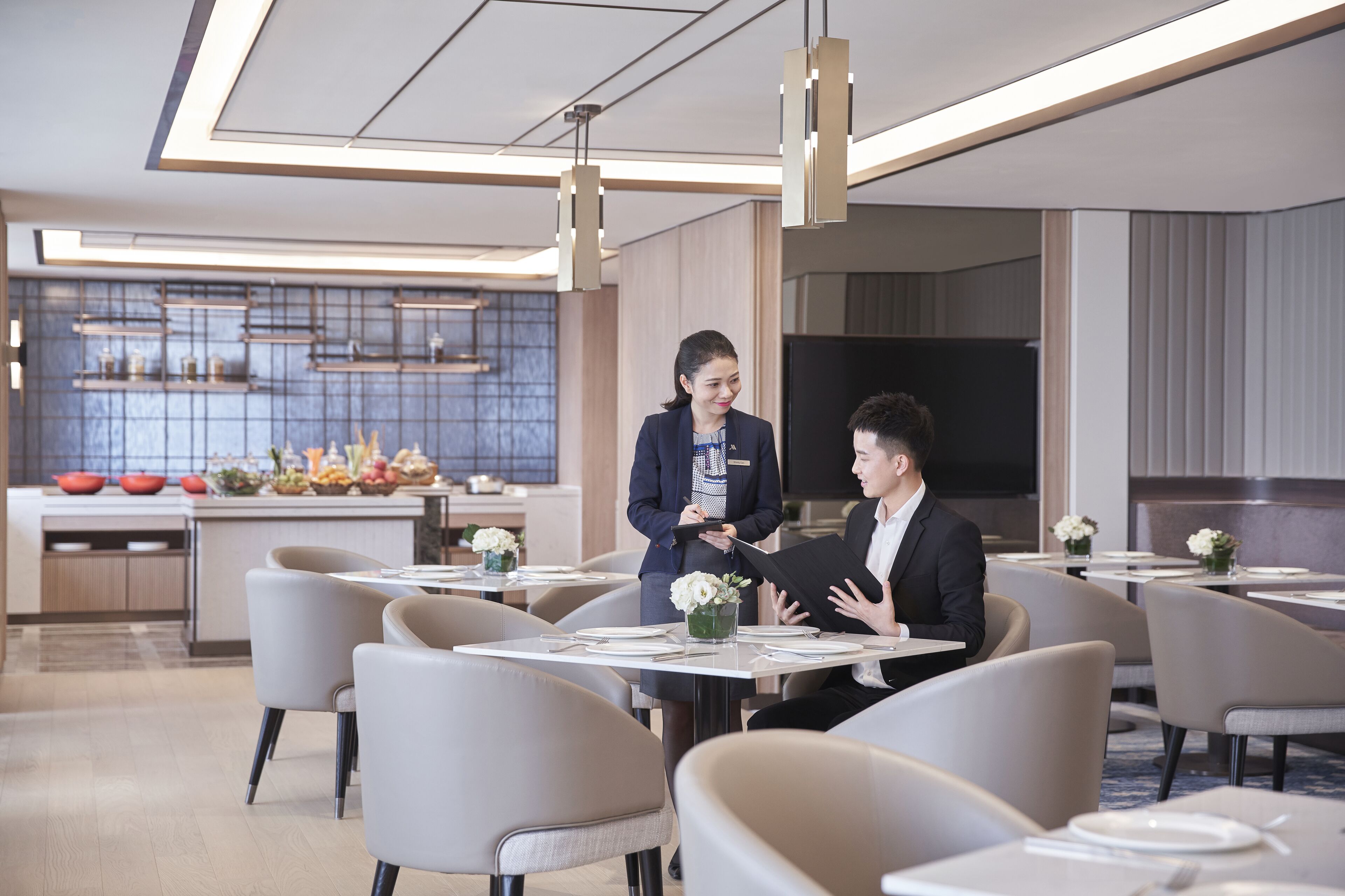 A modern dining area with tables, chairs, and a waiter.